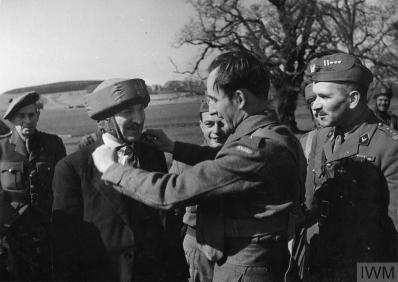 THE POLISH ARMY IN BRITAIN, 1940-1947 (HU 128274) Second Lieutenant of the 1st Polish Independent Parachute Brigade adjusting a bungee helmet (paratrooper's training helmet) on Clement Attlee's head during his visit to the Brigade. Cupar, 20 April 1942. Colonel Stanislaw Sosabowski, the Commander of the Brigade, is on the right. Copyright: © IWM. Original Source: http://www.iwm.org.uk/collections/item/object/205402362